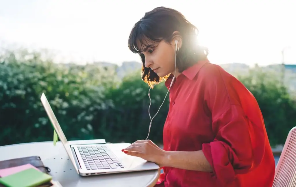 Una mujer con auriculares cuenta lo que necesita por videollamada desde su portátil