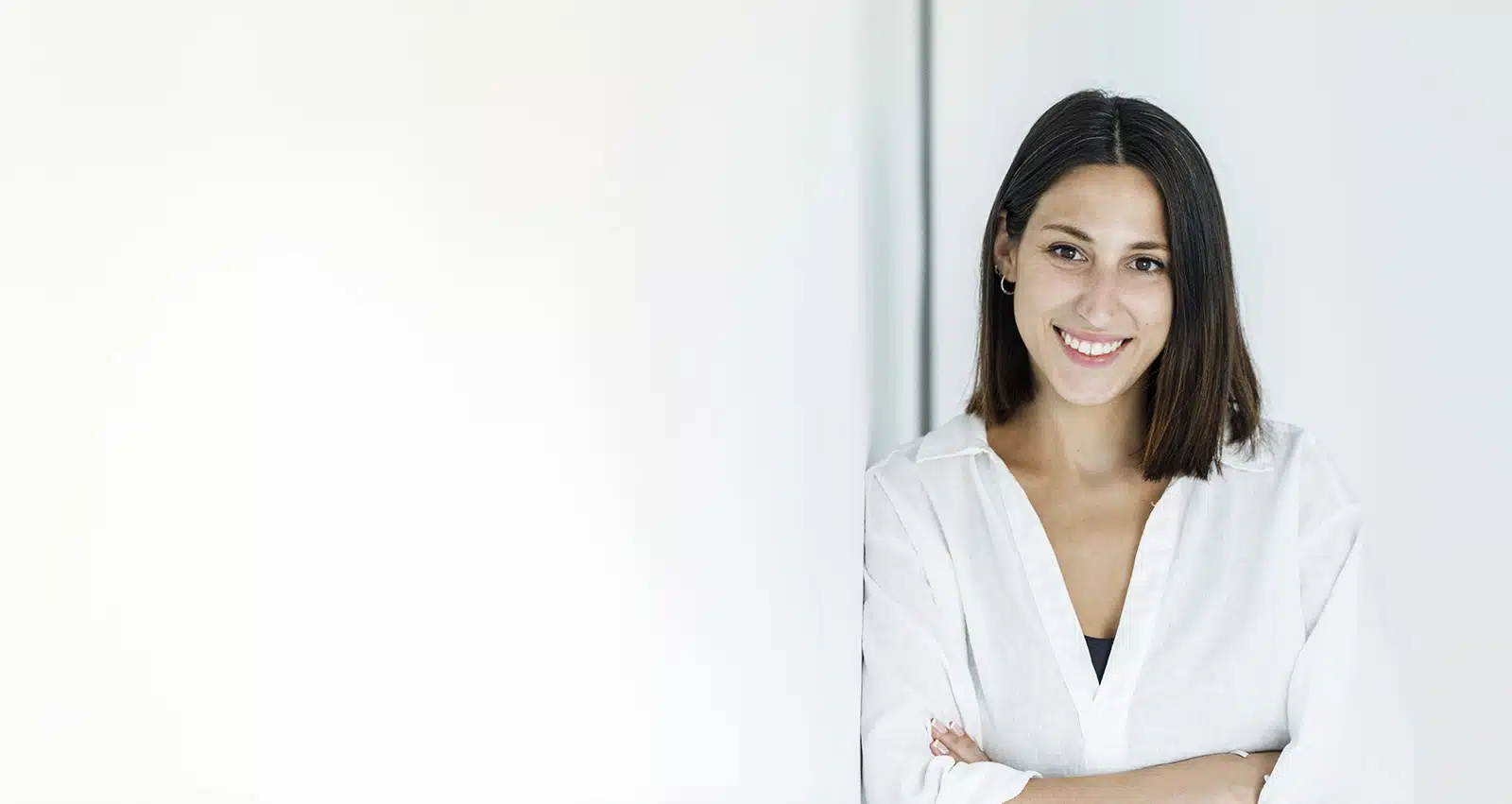 Xiomara Pérez, diseñadora web, sonriendo con los brazos cruzados junto a una pared blanca
