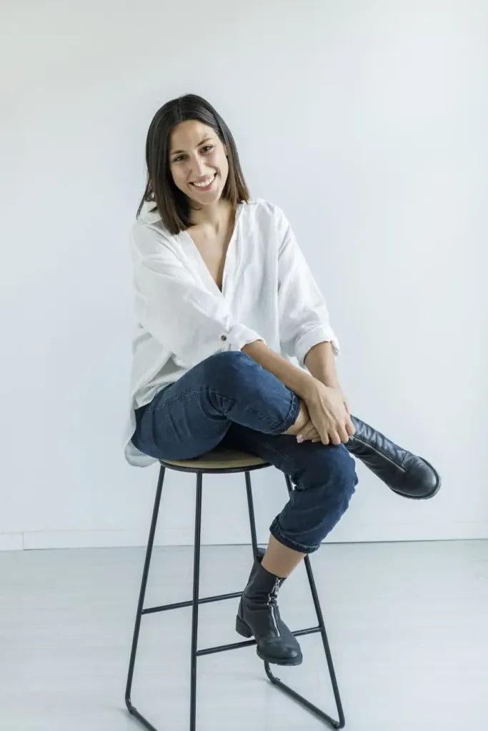 Xiomara Pérez, diseñadora web freelance, sonriendo sentada en un taburete